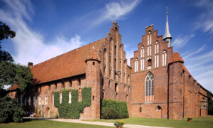 Celle_Kloster_Wienhausen Kloster Wienhausen in Celle, Backsteingebäude mit Zinnen und hohem Giebel bei blauem Himmel.