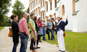 Celle_fuehrung_schloss Stadtführung in Celle mit Gruppe vor historischem Gebäude und grüner Rasenfläche.