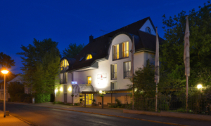 Hoteleingang bei Nacht mit beleuchteter Fassade und wehender Fahne.