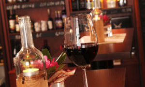 Hotel_Caroline_Mathilde_Celle_Restaurant_Bistro_Kanape_0511_155 Nahaufnahme von gedecktem Tisch mit Rotwein, Weinflasche und Blume.