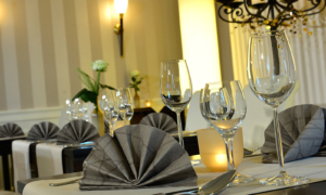 Hotel_Caroline_Mathilde_Celle_Restaurant_Parkblick_0416_011 Elegant gedeckter Tisch mit grauen Servietten, Kerzen und Gläsern im Restaurant.