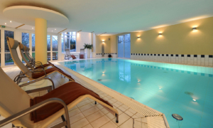 Hotel_Caroline_Mathilde_Celle_Schwimmbad_Pool_Wellness_0112_009 Innenpool mit Liegestühlen, Geländer und ruhiger Wasseroberfläche.