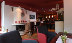 Kanape-Slider Gemütlicher Loungebereich mit roten Sesseln, Kamin, Theke und Wanddeko.